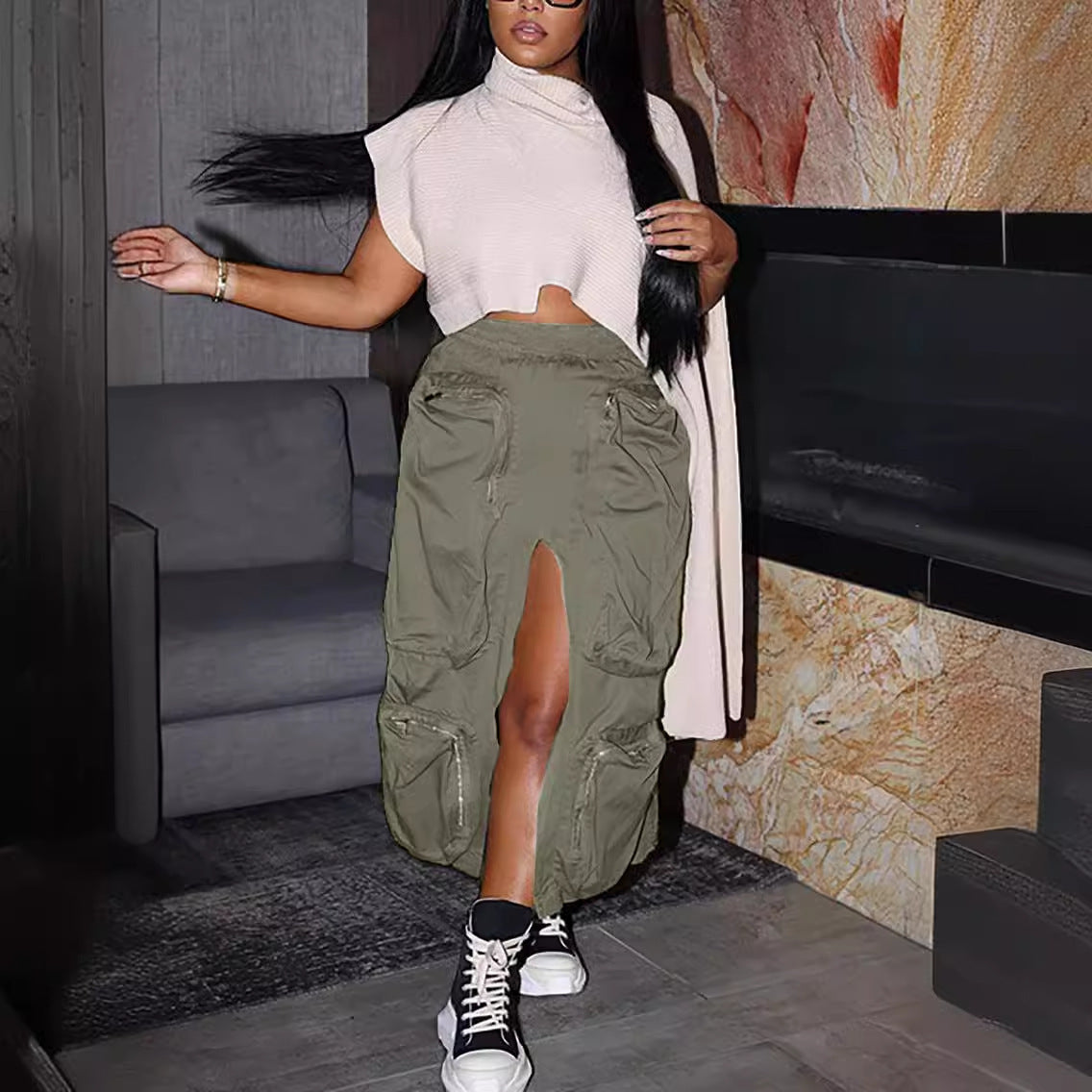 Woman wearing a white top and green cargo pants with a high slit, standing in a modern interior setting.