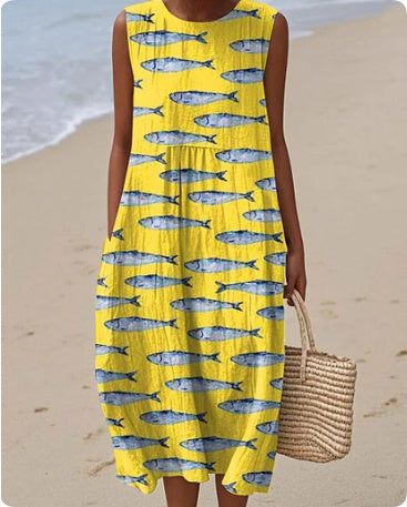 Person wearing a yellow dress with fish pattern on a beach