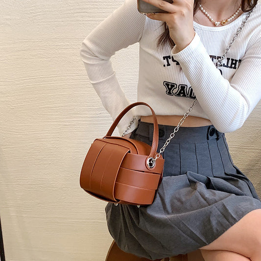Person holding a brown handbag against a neutral background