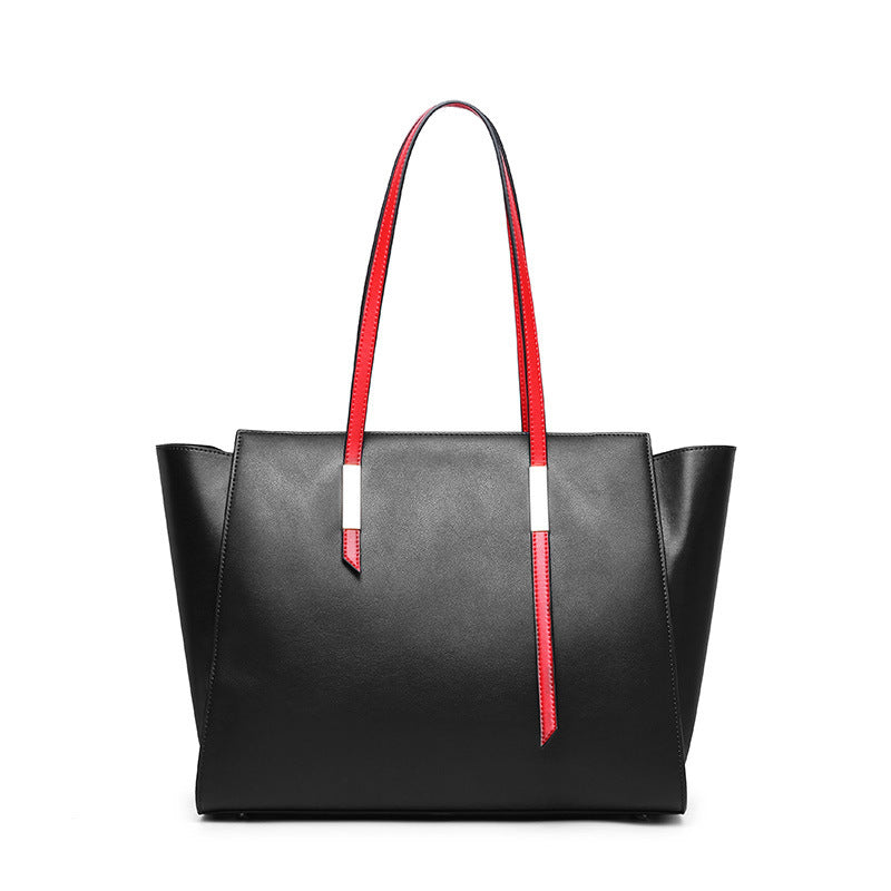 Black tote bag with red handles on a white background