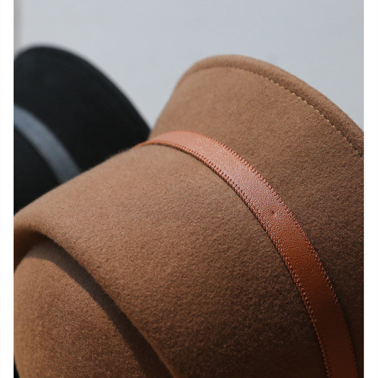 Close-up of a Brown Bucket Hat  with brown leather strap on a textured surface with a blurred background