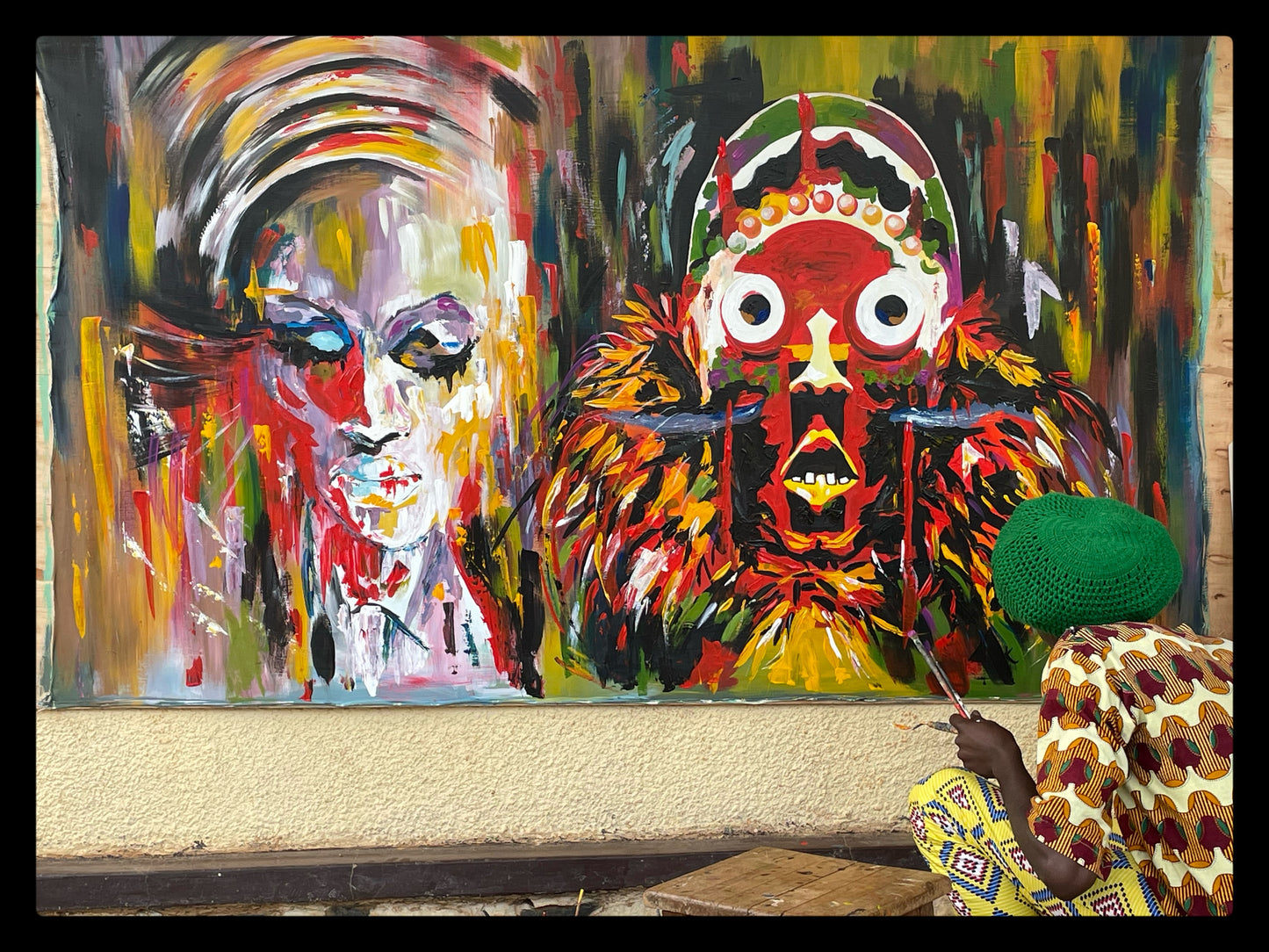 burundi rasta man paints large painting of african mask and spectral woman with headwrap in acrylic paint on canvas